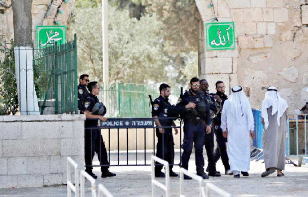 Palestinians walk next to Israeli security forces at the entrance of Al-Aqsa Mosque compound on Tuesday morning after Israel removed metal detectors. — Reuters