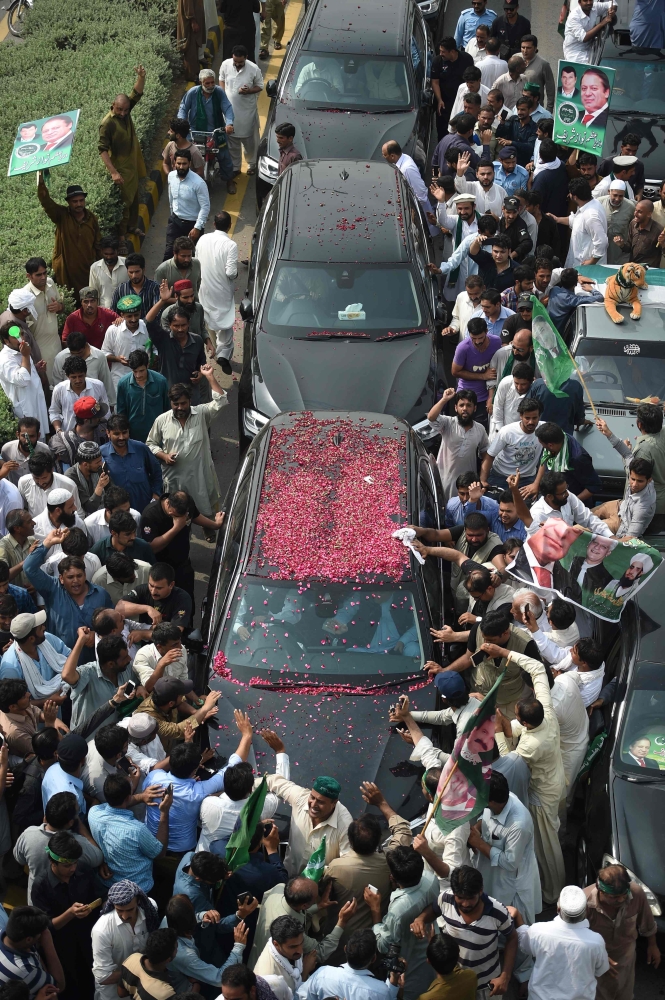 Deposed Pakistani Prime Minster Nawaz Sharif, center left, waves to supporters from his car as he begins a rally from Islamabad to Lahore in Islamabad on Wednesday. — AFP