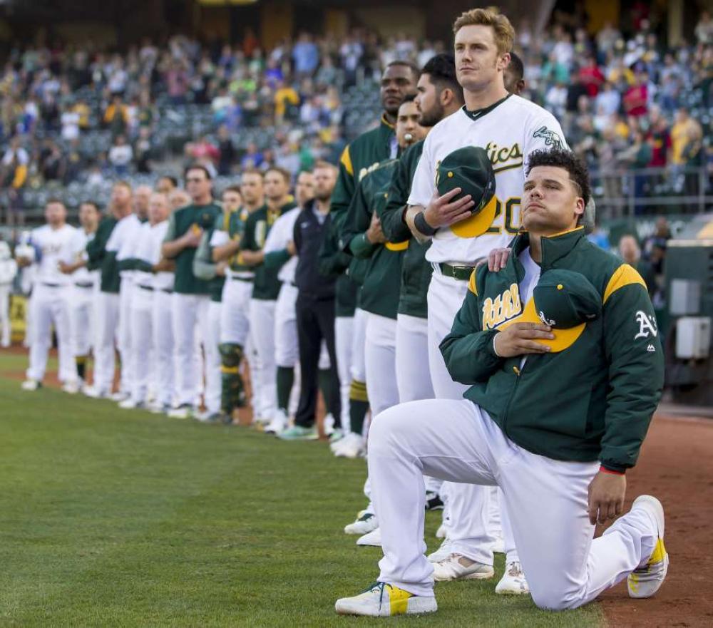 Oakland Athletics catcher Bruce Maxwell kneels during the anthem as teammate Mark Canha puts his hand on Maxwell’s shoulders before their MLB game against Texas Rangers at Oakland Coliseum Saturday. — Reuters