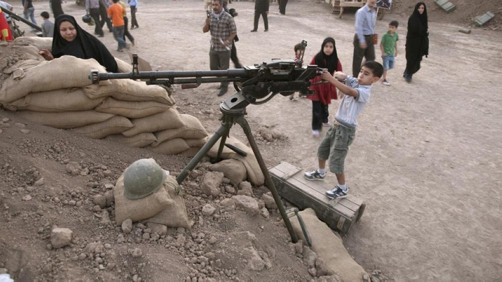 An Iranian boy plays with a weapon at a war exhibition in Tehran. — Reuters