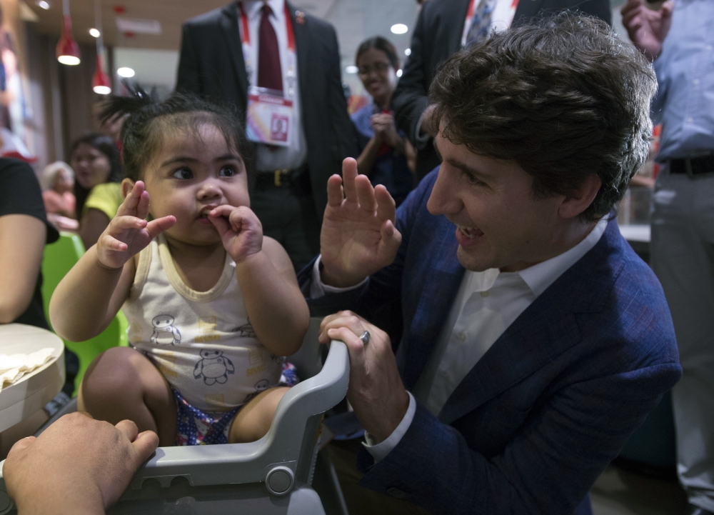 A young girl waves to Canadian Prime Minister Justin Trudeau as he tours a fast food restaurant in Manila, Philippines, on Sunday. — AP