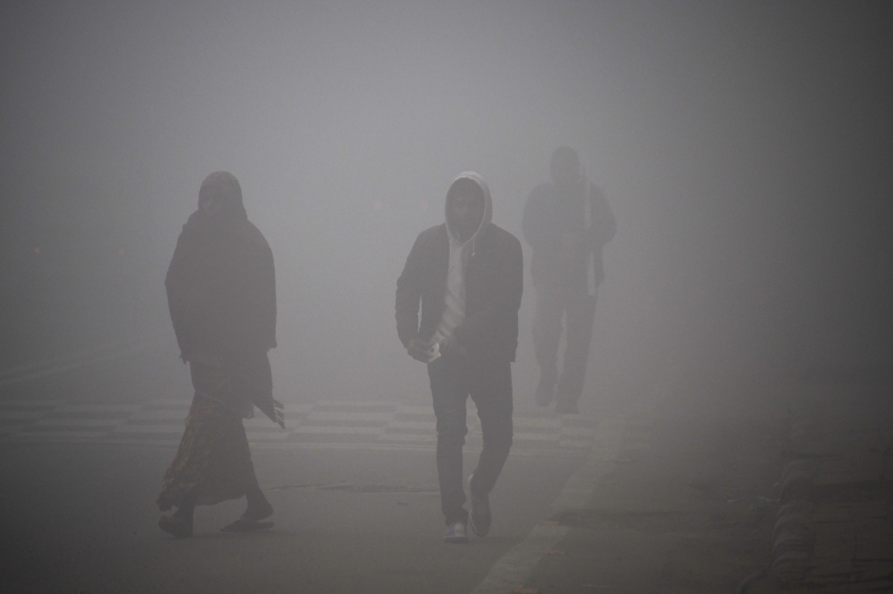 People walk amid heavy smog in a street of New Delhi on Monday. — AFP