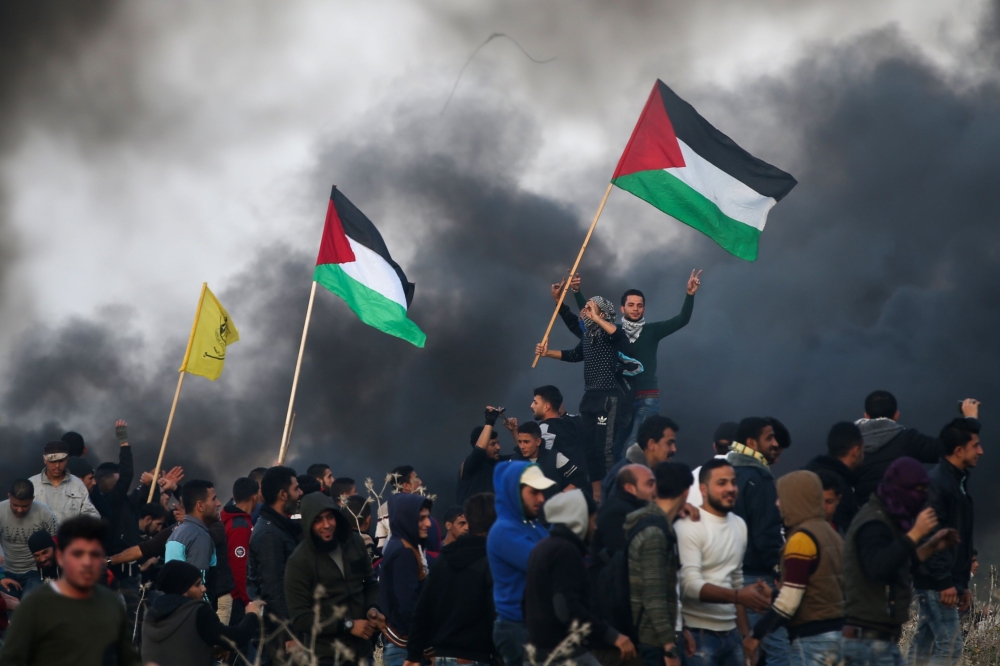 Palestinian protesters wave national flags during clashes with Israeli security forces on the eastern outskirts of Gaza City. — AFP