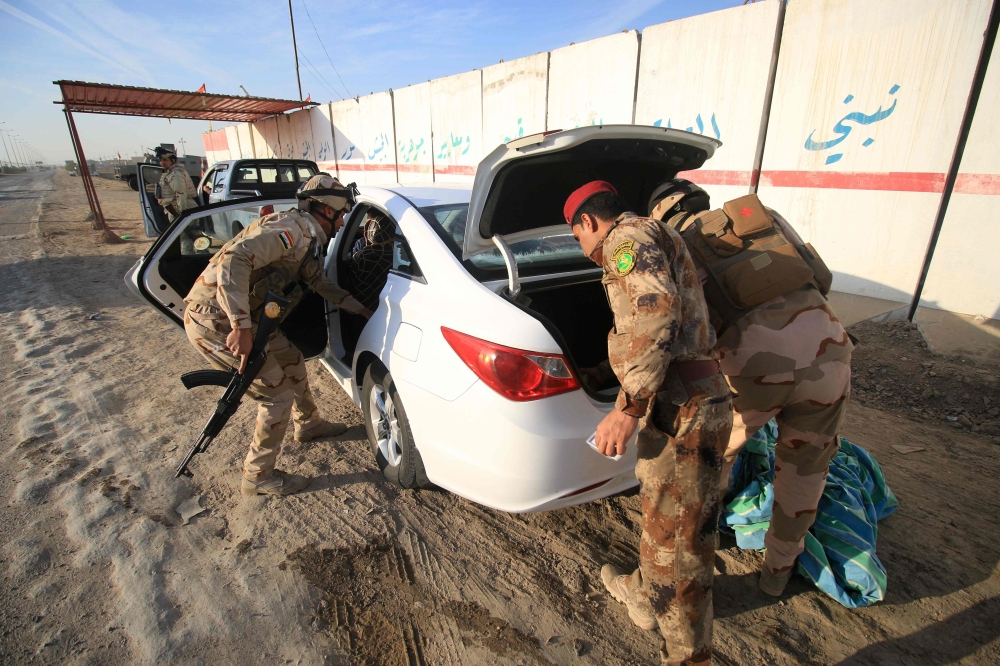 Iraqi soldiers search a vehicle as they control one of several checkpoints they set up along the main 50 km road between the area of Karmat Ali on the northern outskirts of Basra and the town of Al-Dayr as they search for weapons and wanted people involved in tribal conflicts in the north of the Basra province.  — AFP