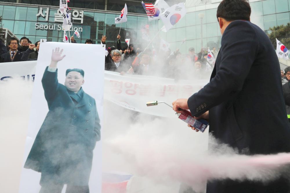 South Korean portesters try to burn a picture of North Korean leader Kim Jong-Un during an anti-North Korea rally outside Seoul station on Monday as a North Korean delegation arrives at the station. — AFP