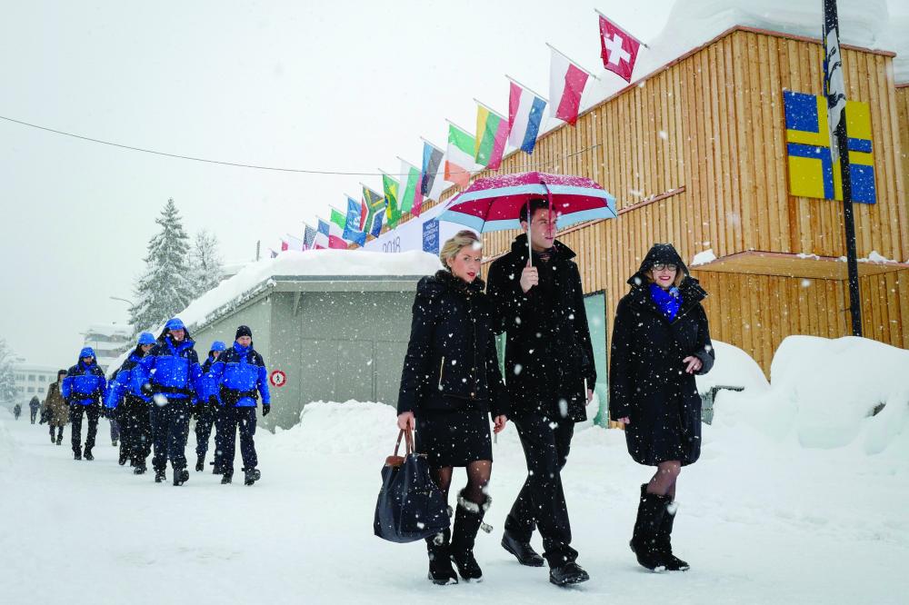 People walk through the resort town of Davos as snow falls ahead of the World Economic Forum (WEF) 2018 annual meeting, on Tuesday in Davos, eastern Switzerland. — AFP