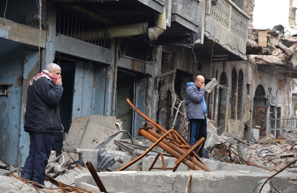 Iraqi men cover their noses as they check a site in the city of Mosul where bodies of alleged Daesh group militants remain. — AFP