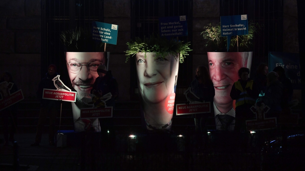 Activists protest with giant portraits of leader of the Social Democratic Party (SPD) Martin Schulz, left, German Chancellor and leader of the Christian Democratic Union (CDU) Angela Merkel, center, and chairman of the Bavarian Christian Social Union (CSU), Horst Seehofer, during a protest about the agrarian reform, in front of the SPD’s headquarters, Willy-Brandt-Haus, ahead of the coalition talks to form a new government, on Tuesday in Berlin. — AFP