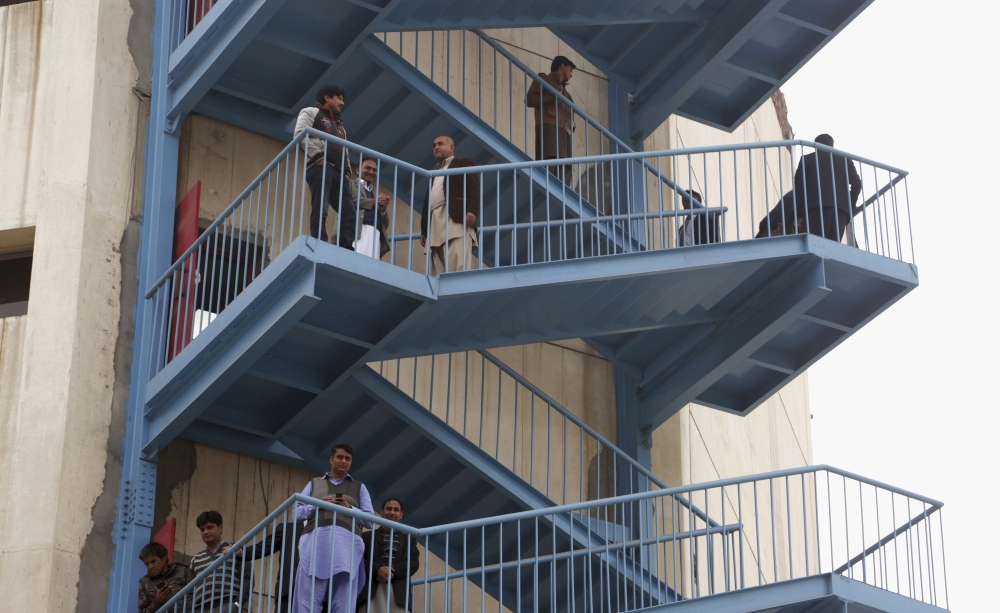 People stand on stairs outside their offices after a severe earthquake is felt in Lahore, Pakistan, on Wednesday. — AP