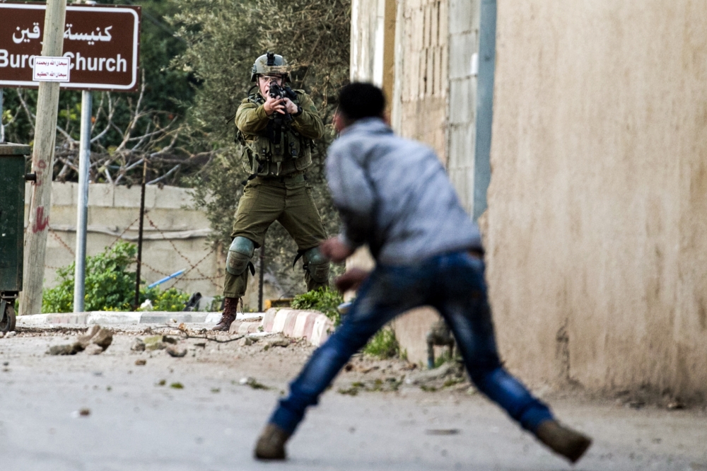 A Palestinian protester confronts an Israeli soldier during an army search operation in the Palestinian village of Burqin, about 18 kilometers northwest of Nablus in the occupied West Bank. — AFP