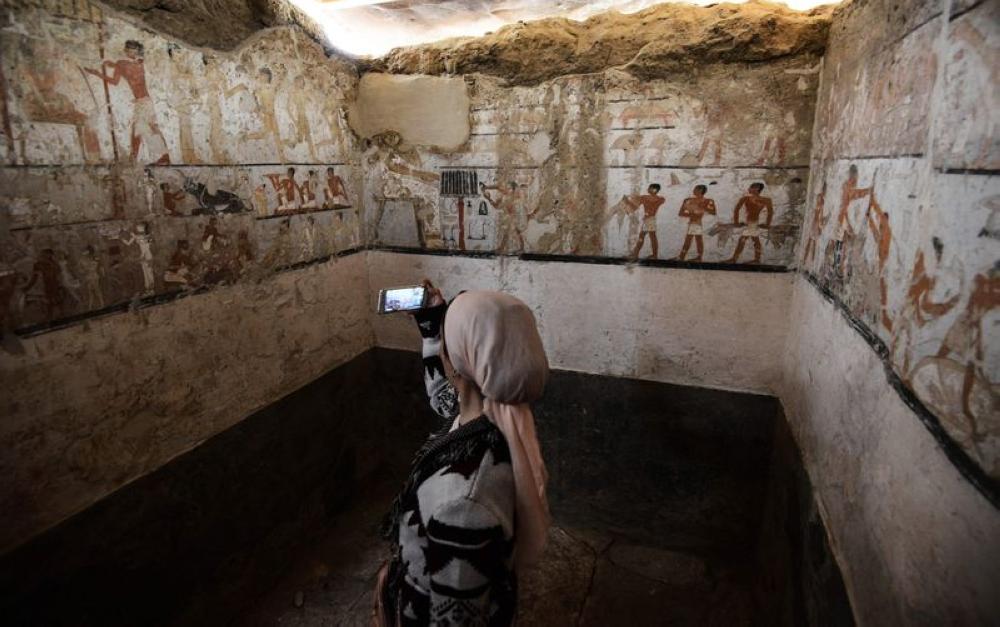 A woman takes a photo inside the tomb of an Old Kingdom priestess adorned with well-preserved and rare wall paintings on the Giza plateau in Cairo. — AFP