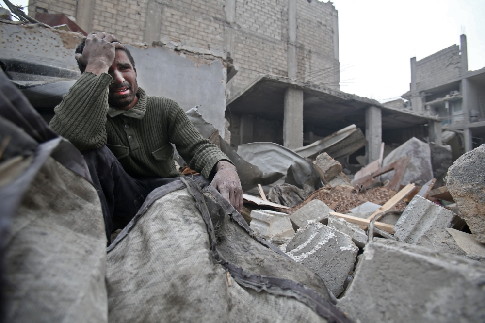 A Syrian man mourns over his destroyed home in the rebel-held besieged town of Arbin, in the eastern Ghouta region on the outskirts of the capital Damascus following regime air strikes. — AFP