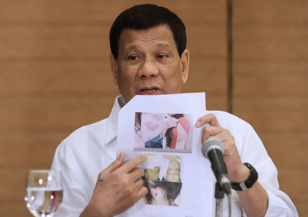 Philippine President Rodrigo Duterte shows a photo of a Filipina worker in Kuwait, of whom he said she had been 