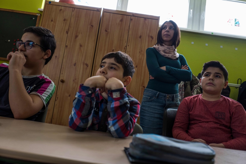 Syrian teaching assistant Hend Al Khabbaz (Up C) coaches young Syrian refugee pupils (C and R) during class at the Sigmund-Jaehn-Grundschule (primary school) in Fuerstenwalde, eastern Germany. — AFP