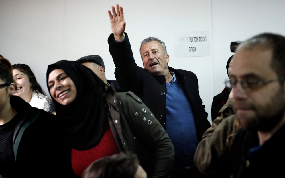 Bassem Tamimi (C), the father of 17-year-old Palestinian Ahed Tamimi waves as she arrives for the beginning of her trial in the Israeli military court at Ofer military prison in the West Bank village of Betunia on Tuesday.  — AFP