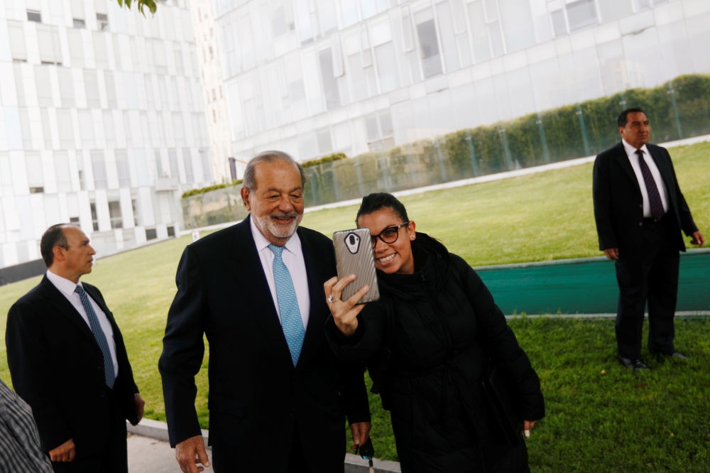 Mexican billionaire Carlos Slim poses for a selfie with a woman after he attends a ceremony to place the first stone of the new US Embassy in Mexico City on Tuesday. — Reuters