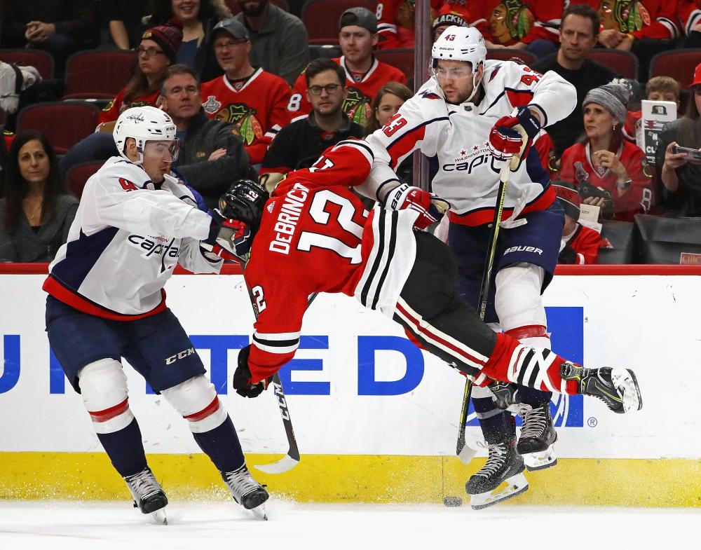 Alex DeBrincat (C) of the Chicago Blackhawks collides with Tom Wilson (R) and Dmitry Orlov of the Washington Capitals at the United Center in Chicago Saturday. — AFP