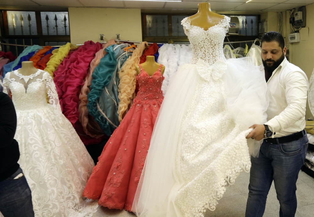 A Syrian man arranging dresses at a wedding dresses shop in the capital Damascus. For many Syrian women, aged 30 and older, who are eager to get married -- Syria's protracted conflict means potential suitors have emigrated, joined the army or lost their lives.  — AFP