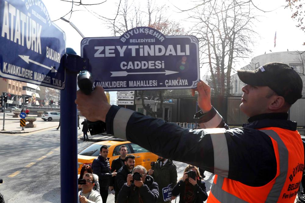 

A municipal worker changes a sign outside the US embassy in Ankara on Monday to rename a street, Zeytindali (Olive branch) after Turkey’s operation against a Kurdish militia in Syria. — AFP