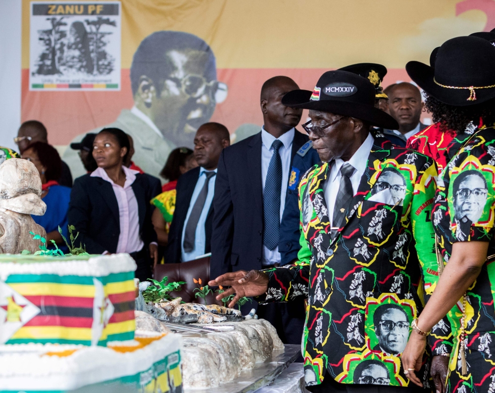 Zimbabwean President Robert Mugabe admires a cake made for his 93rd birthday celebrations hosted at Rhodes Preparatory School in Matopos, Matabeleland South Province, South Africa, in this Feb. 25, 2017 file photo. — AFP