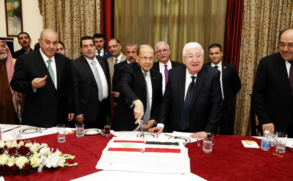 A handout picture provided by the Lebanese photo agency Dalati and Nohra on February 20, 2018 shows Lebanese President Michel Aoun (C-L) cutting a cake with the Iraqi President Fuad Masum (C-R) earing the flags of both countries, during the former's official visit to the Iraqi capital Baghdad, accompanied by former Iraqi Prime Ministers Iyad Allawi (L) and Nuri al-Maliki (R). === RESTRICTED TO EDITORIAL USE - MANDATORY CREDIT 