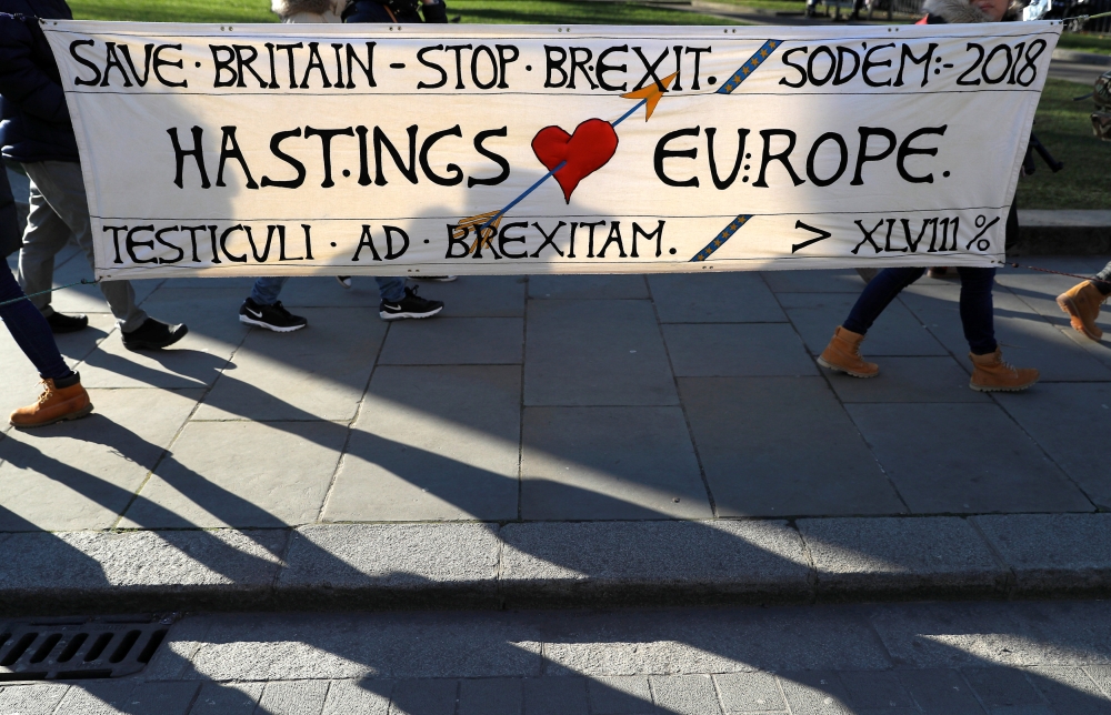 Tourists walk past an anti-Brexit banner displayed opposite the Palace of Westminster in London, Britain, on Thursday. — Reuters