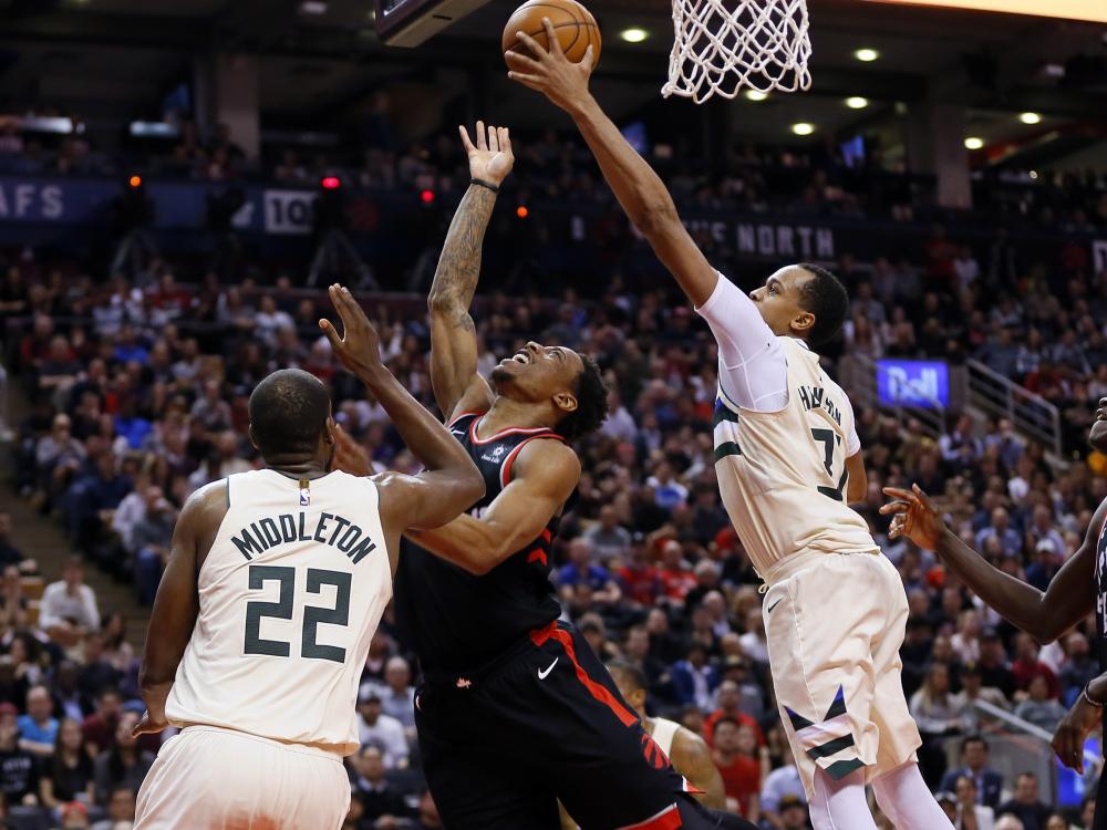 Milwaukee Bucks’ center John Henson (R) and guard Khris Middleton (L) defend against Toronto Raptors’ guard DeMar DeRozan during their NBA game at the Air Canada Centre in Toronto Friday. — Reuters
