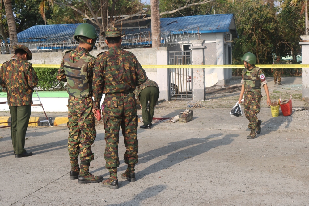 Members of the military and police stand near the site of an early morning explosion in the compound of the state government secretary’s home in Sittwe, Rakhine State, on Saturday. — AFP