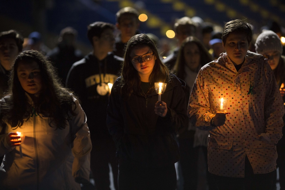 Led by high school students, mourners walk around the track of the football field with candles during a community vigil at Newtown High School for the victims of last week’s mass shooting at Marjory Stoneman Douglas High School in Parkland, Florida, Newtown, Connecticut, on Friday. — AFP
