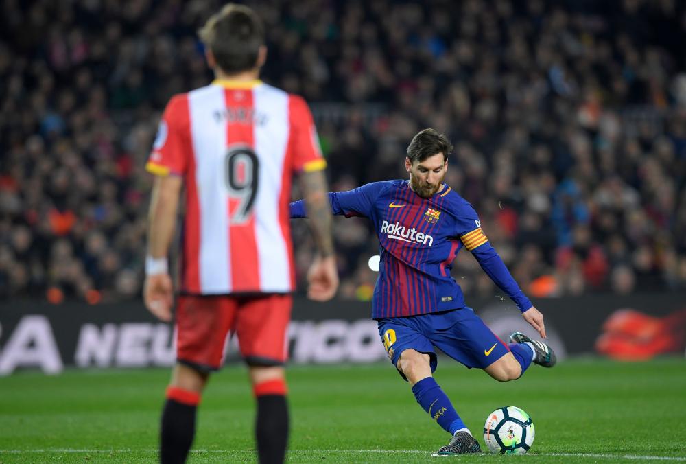 Barcelona’s Lionel Messi (R) kicks the ball during their Spanish league football match against Girona FC at the Camp Nou Stadium in Barcelona Saturday. — AFP