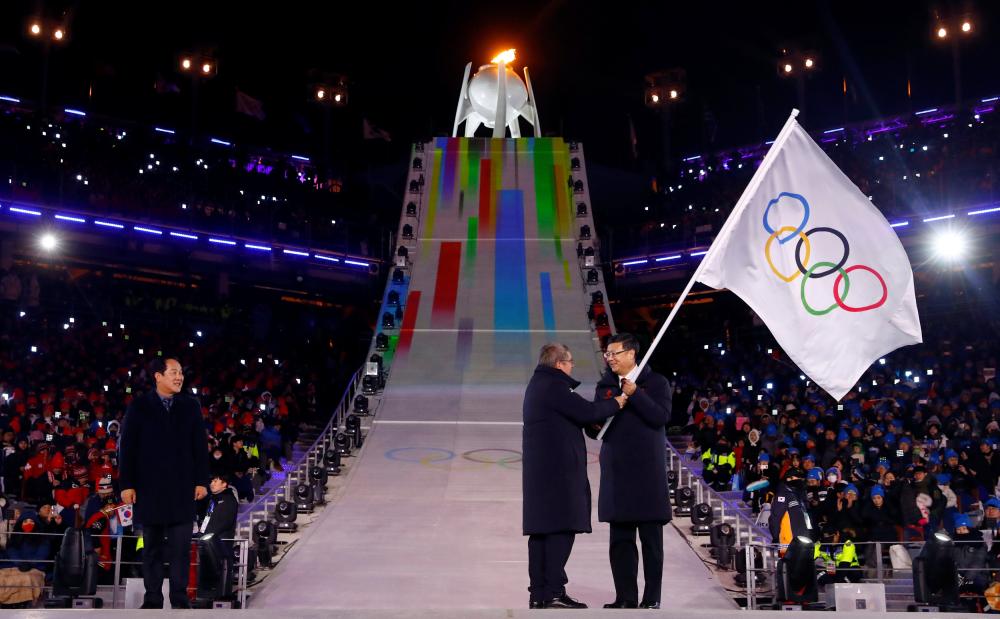 IOC President Thomas Bach (C) hands over the Olympic flag to Beijing Mayor Chen Jining as Pyeongchang Mayor Shim Jae Kook looks on during the closing ceremony of the Pyeongchang 2018 Winter Olympics Sunday. — Reuters