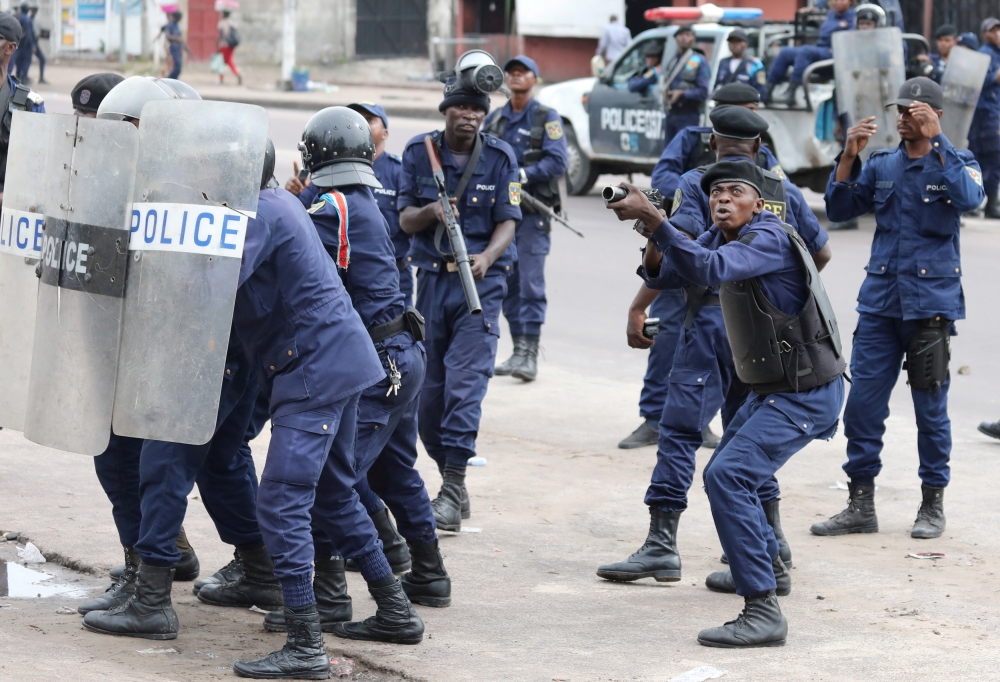 Policemen react after a protester threw a stone from Notre Dame Cathedral compound in Kinshasa, Democratic Republic of Congo, on Sunday. — Reuters