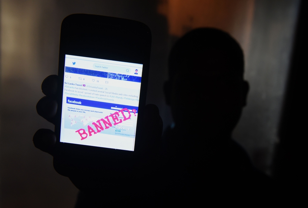 A Sri Lankan man mobile phone user holds up a message twitter showing that Facebook had been banned in Colombo on Wednesday. — AFP