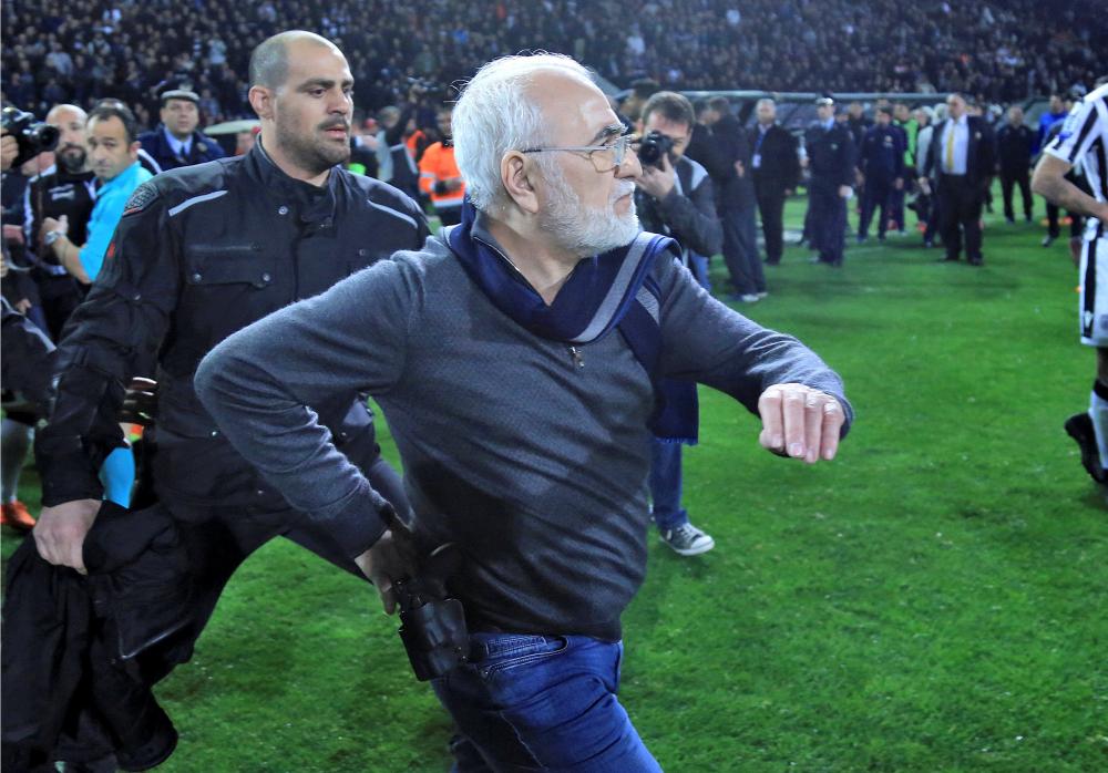 Russian-born Greek businessman and owner of PAOK Salonika, Ivan Savvides (C), pictured with what appears to be a gun in a holster, enters the pitch after the referee annulled a goal of PAOK during their soccer match against AEK Athens in Toumba Stadium in Thessaloniki Sunday. — Reuters