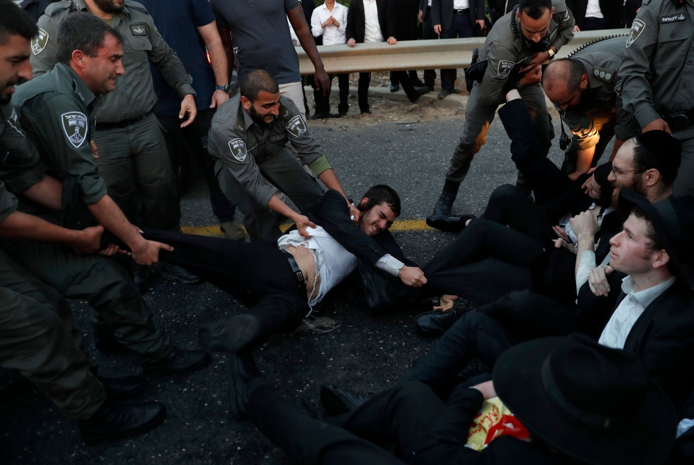 Israeli police remove Ultra-Orthodox Jewish demonstrators who are blocking a road during a protest against Israeli army conscription in the town of Bnei Brak, near Tel Aviv. — AFP