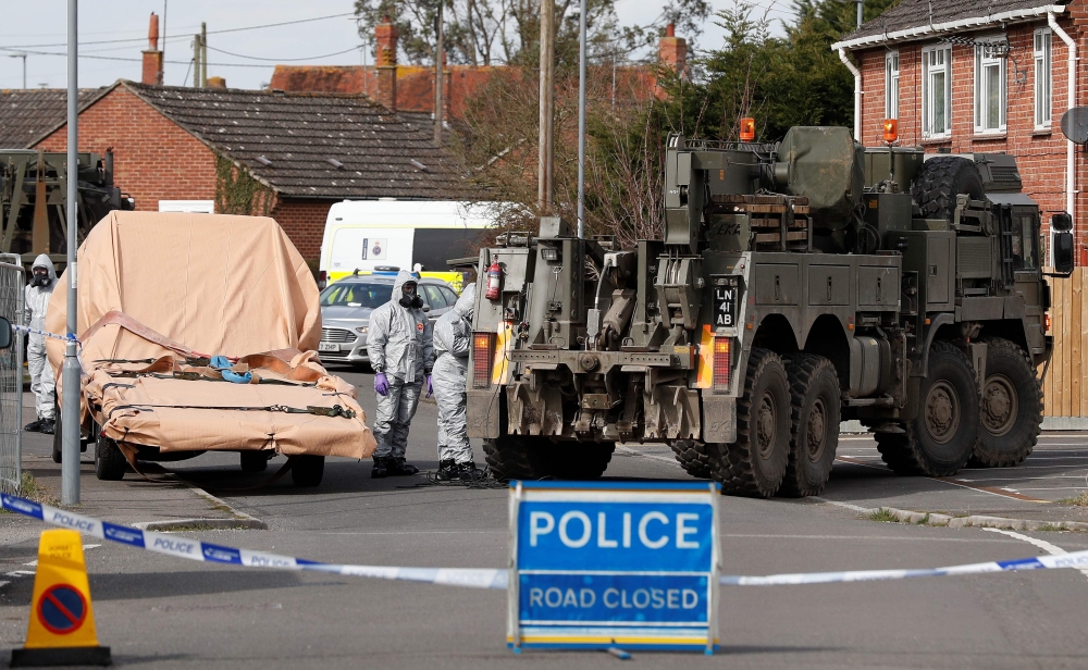 British Military personnel wearing protective coveralls work to remove a vehicle connected to the March 4 nerve agent attack in Salisbury, from a residential street in Gillingham, southeast England on Wednesday. — AFP