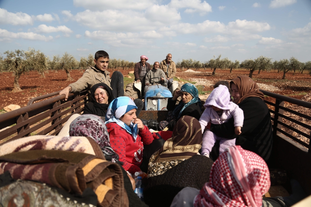 Syrian civilians fleeing Afrin after Turkey said its army and allied rebels surrounded the Kurdish city in northern Syria, pass through the village of Anab northwest of the city, on Tuesday. — AFP