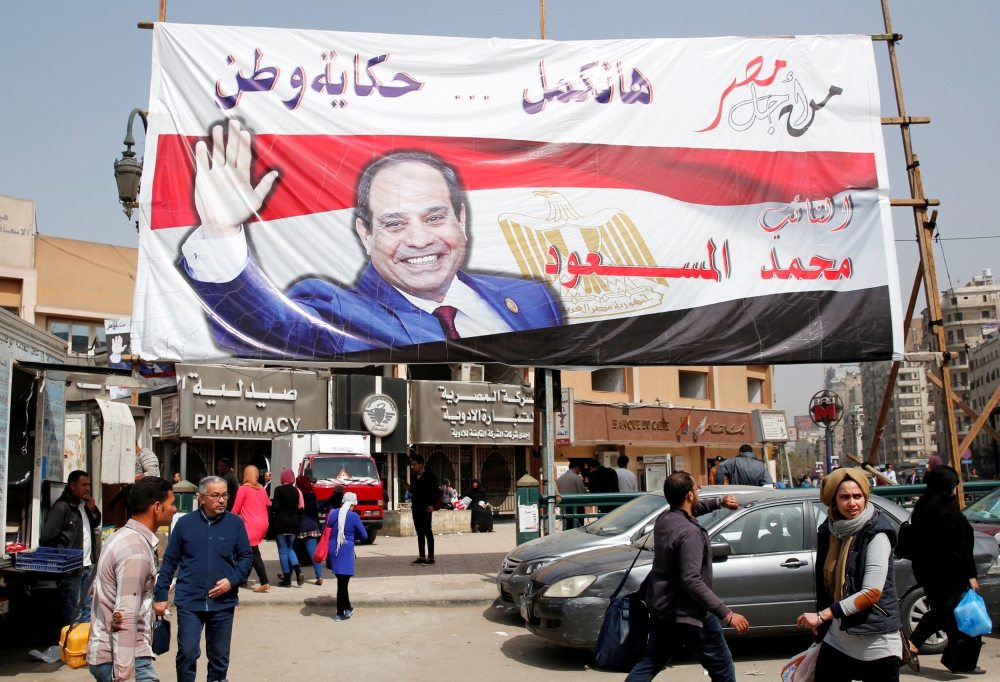 People walk by a poster of Egyptian President Abdel-Fattah El-Sissi for the upcoming presidential election in Cairo in this March 1, 2018 file photo. — Reuters