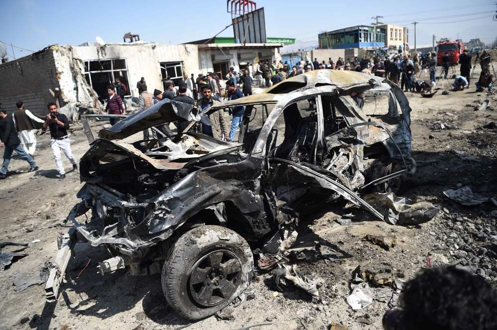 Afghan security personnel and civilians gather next to a damaged car at the site of a car bomb attack in Kabul on Saturday. — AFP