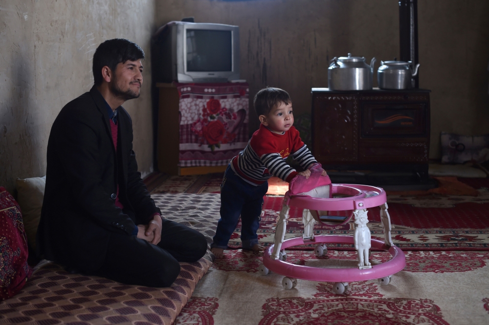 Afghan father Sayed Assadullah Pooya, 28, looks on alongside his son Donald Trump, aged around 18 months, during an interview at their home in Kabul on Friday. — AFP