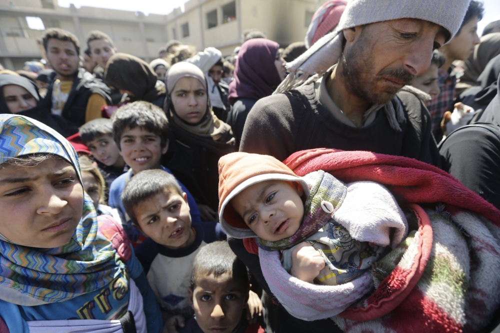 Syrian civilians, evacuated from rebel-held areas in the Eastern Ghouta, gather at a school in the regime-controlled Hosh Nasri, on the northeastern outskirts of the capital Damascus. — AFP