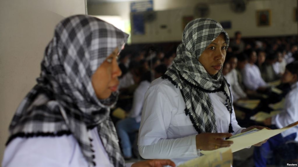 Indonesian migrant workers heading for Middle East countries hold their passports at an immigration office. — Reuters file photo