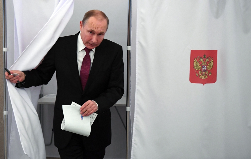 Presidential candidate, President Vladimir Putin walks out of a voting booth at a polling station during Russia’s presidential election in Moscow on Sunday. — AFP