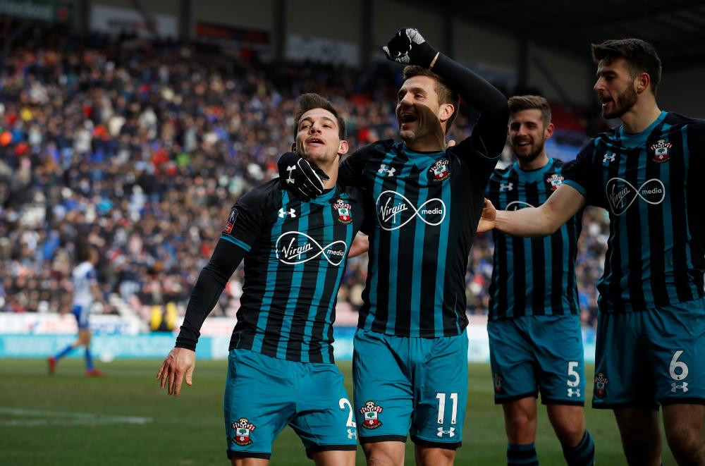 Southampton's Cedric Soares celebrates scoring their second goal with Dusan Tadic and teammates against Wigan Athletic during the FA Cup quarterfinal match at DW Stadium, Wigan, Sunday. — Reuters