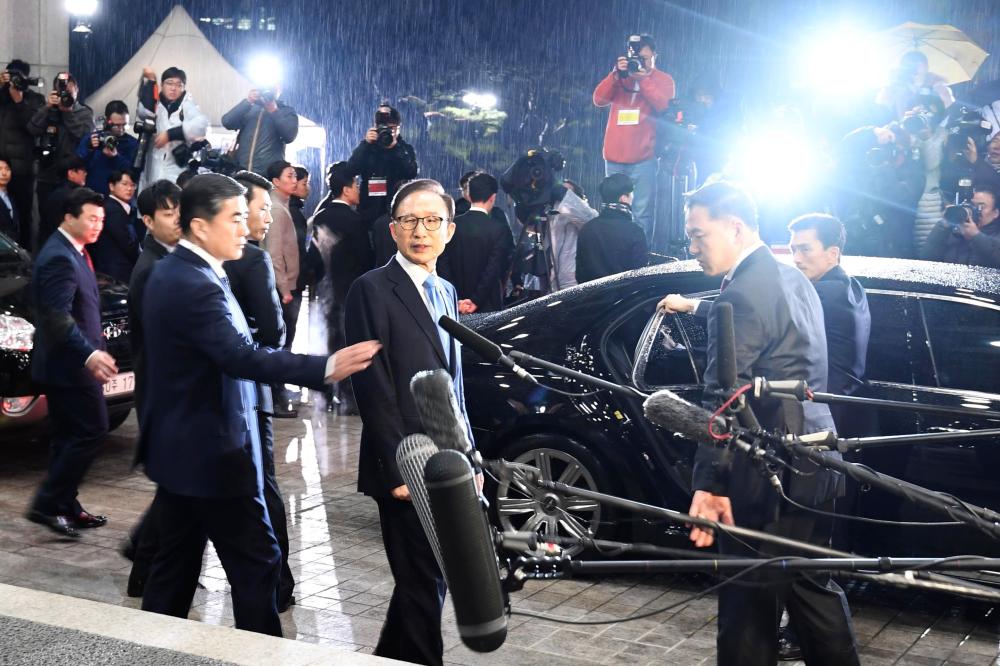 Former South Korean President Lee Myung-bak, center, leaves the prosecutors’ office in Seoul in this March 15, 2018 file photo. — AFP