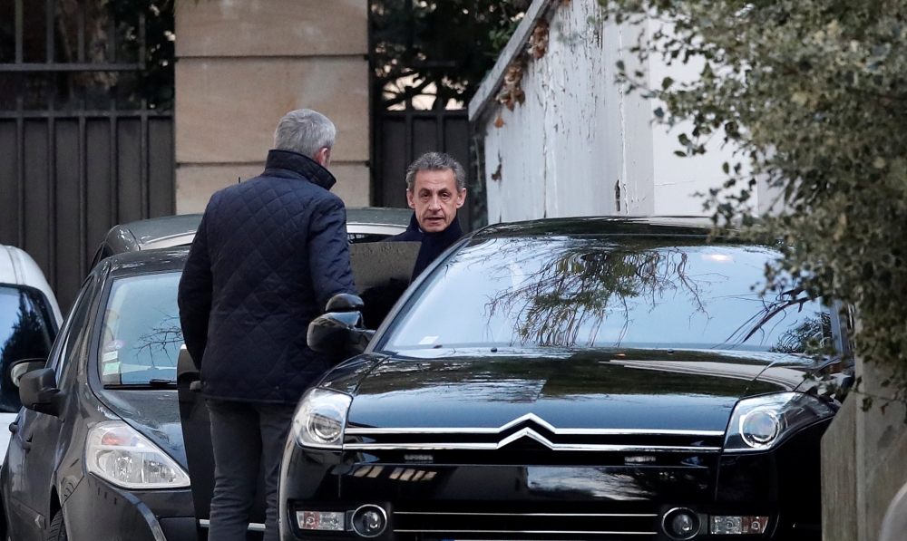 Former French President Nicolas Sarkozy enters his car as he leaves his house in Paris on Wednesday. — Reuters