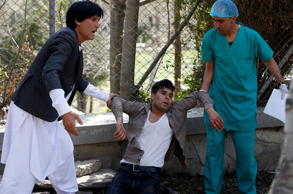 Afghan men mourn at a hospital compound after a suicide attack in Kabul, Afghanistan, on Wednesday. — Reuters