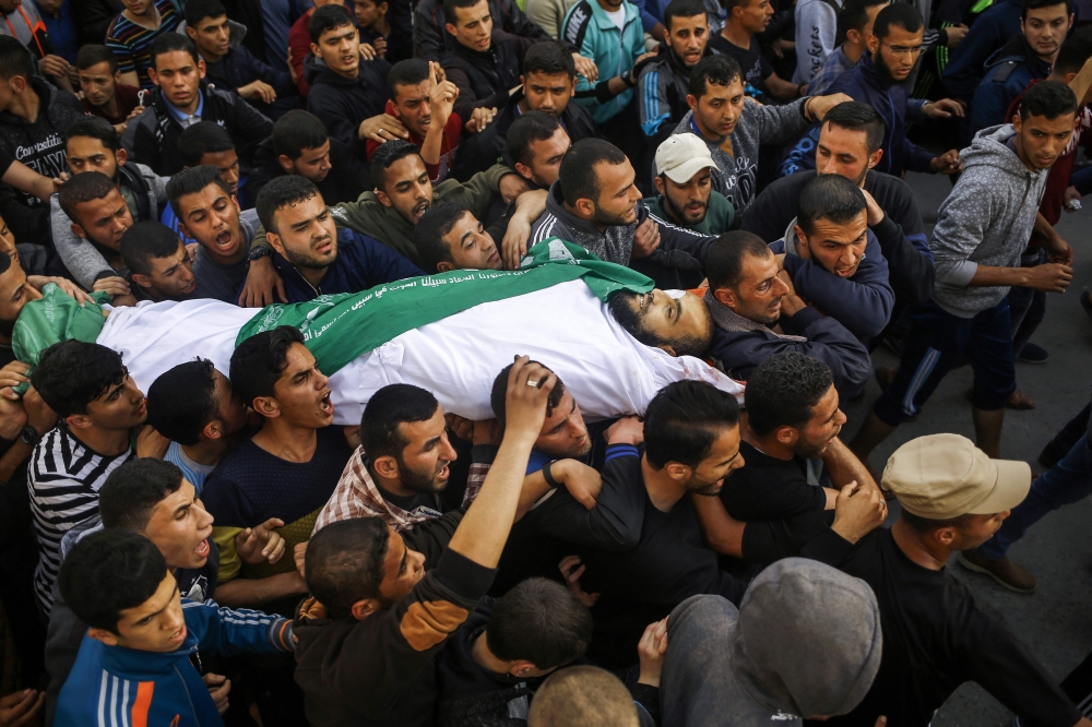Mourners carry the body of Ziad Al-Howajri, one of the members of Hamas’ security forces, during his funeral in Al-Nusairat refugee camp in the central Gaza Strip on Thursday, after he was killed with a comrade while attempting to arrest a suspect in a bomb attack against the Palestinian prime minister during his visit to the enclave on March 13.— AFP