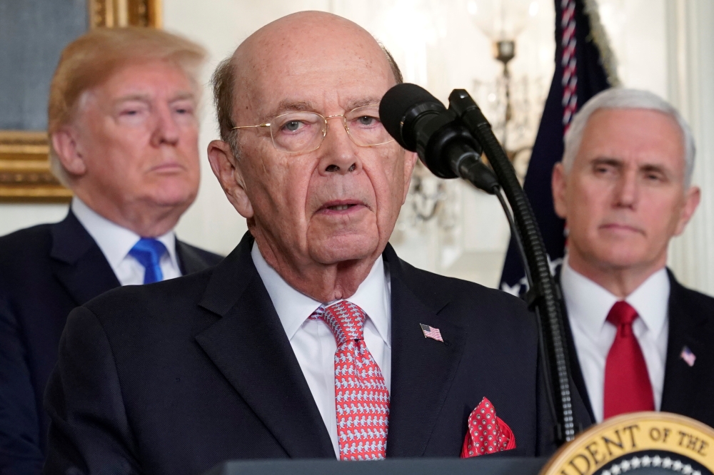 US President Donald Trump, flanked by ‪Vice President Mike Pence‬, listens to remarks by Commerce Secretary Wilbur Ross before signing a memorandum on intellectual property tariffs on high-tech goods from China, at the White House in Washington, US, on Thursday. — Reuters