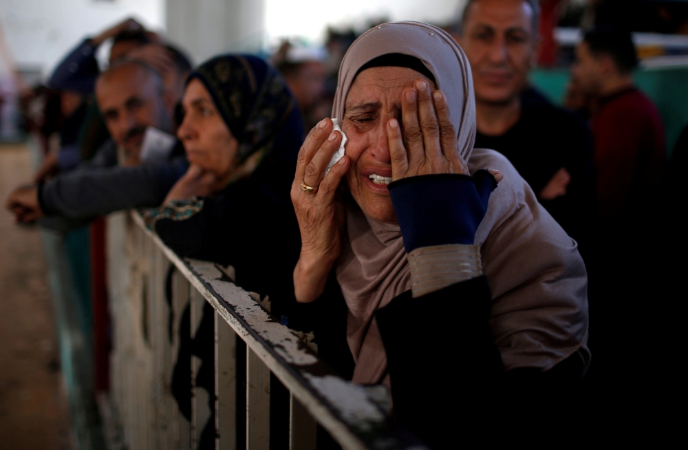 A Palestinian woman reacts as she waits for a travel permit to cross into Egypt through the Rafah border crossing after it was opened by Egyptian authorities for humanitarian cases, in the southern Gaza Strip, on Friday. — Reuters